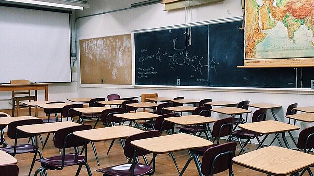 Ein leeres Klassenzimmer mit Stühlen und Pulten.