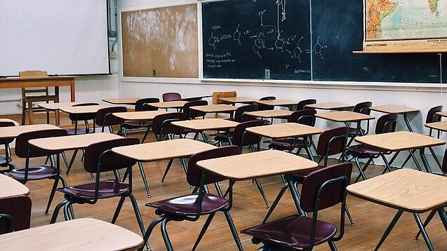 Ein leeres Klassenzimmer mit Stühlen und Pulten.