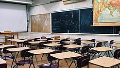 Ein leeres Klassenzimmer mit Stühlen und Pulten.