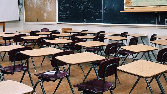 Ein leeres Klassenzimmer mit Stühlen und Pulten.