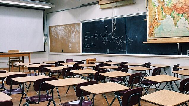 Ein leeres Klassenzimmer mit Stühlen und Pulten.