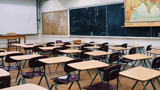 Ein leeres Klassenzimmer mit Stühlen und Pulten.