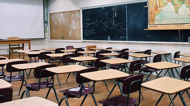 Ein leeres Klassenzimmer mit Stühlen und Pulten.