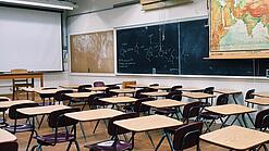 Ein leeres Klassenzimmer mit Stühlen und Pulten.