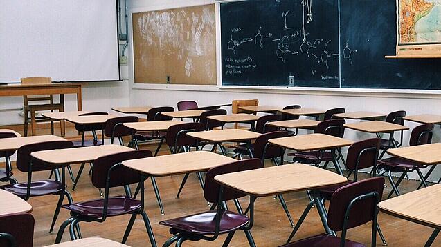 Ein leeres Klassenzimmer mit Stühlen und Pulten.