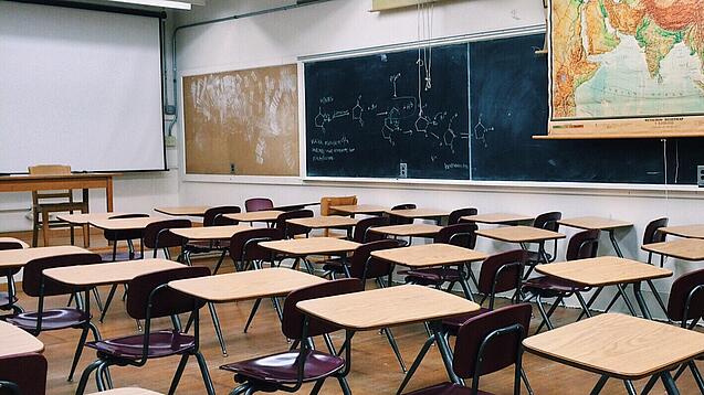 Ein leeres Klassenzimmer mit Stühlen und Pulten.