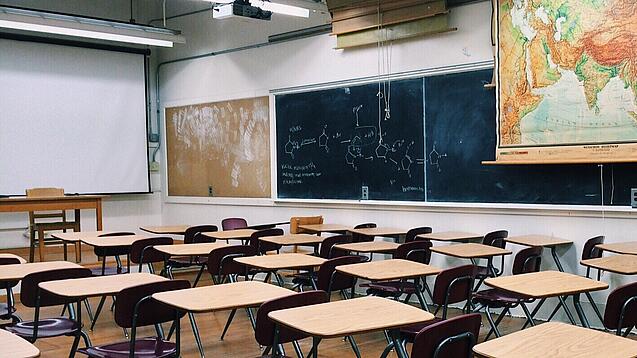 Ein leeres Klassenzimmer mit Stühlen und Pulten.