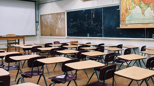 Ein leeres Klassenzimmer mit Stühlen und Pulten.