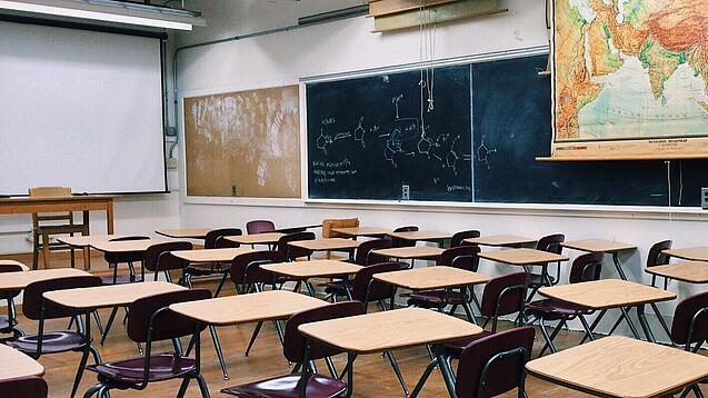 Ein leeres Klassenzimmer mit Stühlen und Pulten.
