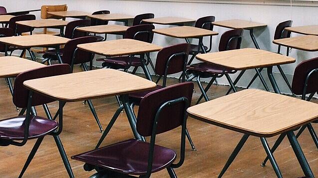 Ein leeres Klassenzimmer mit Stühlen und Pulten.