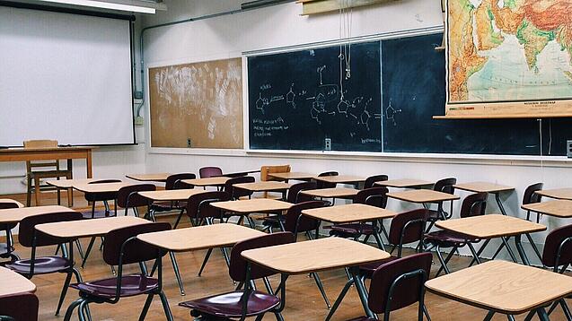 Ein leeres Klassenzimmer mit Stühlen und Pulten.