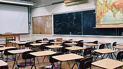 Ein leeres Klassenzimmer mit Stühlen und Pulten.