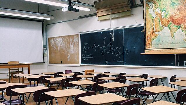 Ein leeres Klassenzimmer mit Stühlen und Pulten.