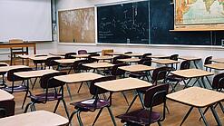 Ein leeres Klassenzimmer mit Stühlen und Pulten.