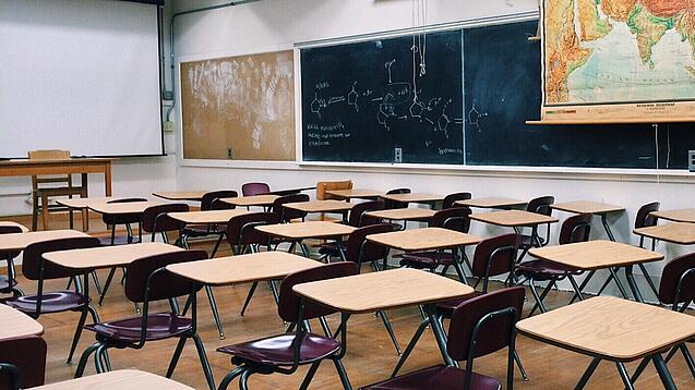 Ein leeres Klassenzimmer mit Stühlen und Pulten.