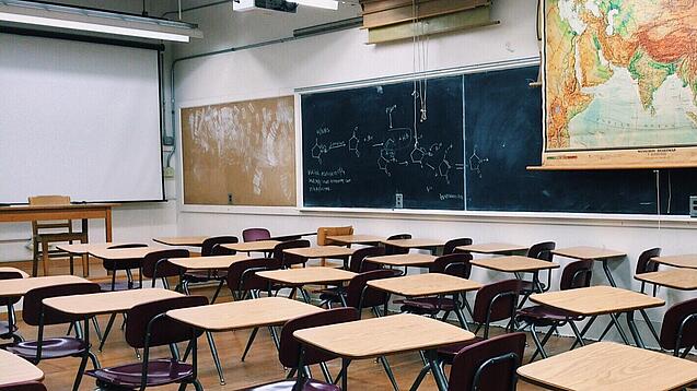 Ein leeres Klassenzimmer mit Stühlen und Pulten.