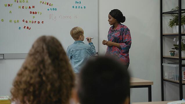 Lehrerin und Schüler an einem Whiteboard.