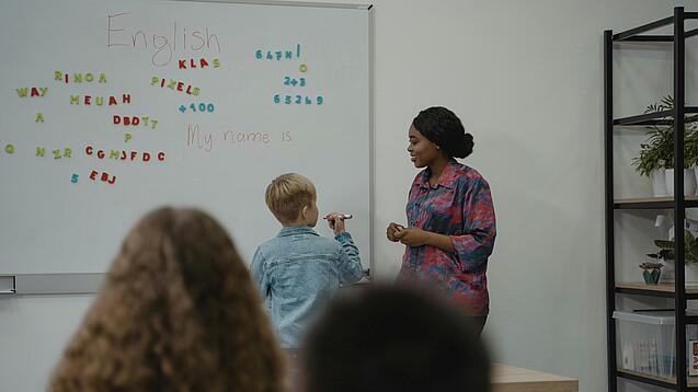 Lehrerin und Schüler an einem Whiteboard.