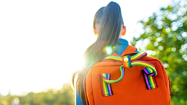 Blick von hinten auf ein Mädchen mit einem Rucksack.