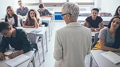 Eine Lehrerin steht vor einer Klasse von Oberstufenschülerinnen.