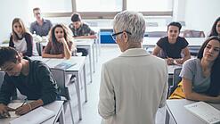Eine Lehrerin steht vor einer Klasse von Oberstufenschülerinnen.