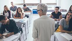 Eine Lehrerin steht vor einer Klasse von Oberstufenschülerinnen.