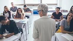 Eine Lehrerin steht vor einer Klasse von Oberstufenschülerinnen.