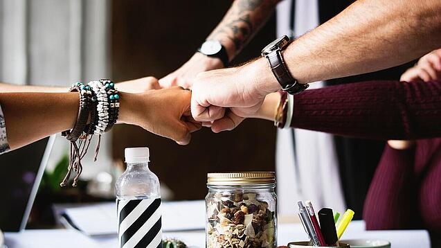 Mehrere Hände treffen sich zum Fistbump.