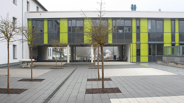 Ein modernes Schulgebäude und der Schulhof.