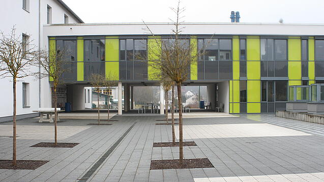Ein modernes Schulgebäude und der Schulhof.