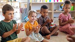 Kindergartenkinder sitzen in einem Kreis und klatschen in die Hände.