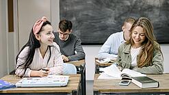 Mehrere Oberstufenschülerinnen und Oberstufenschüler sitzen in einem Klassenraum.