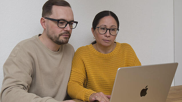 Eltern sitzen vor einem Laptop.