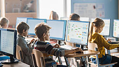 Schülerinnen und Schüler sitzen vor Computern in einem Klassenzimmer.