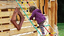 Ein Kind klettert auf einem Spielplatz an einem Spielgerät.