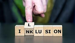 Bausteine mit Buchstaben, die die Wörter Inklusion und Illusion ergeben.