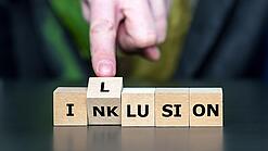 Bausteine mit Buchstaben, die die Wörter Inklusion und Illusion ergeben.