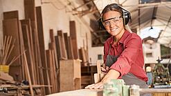 Junge Tischlerin bei der Arbeit an einem Holzstück.
