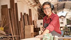 Junge Tischlerin bei der Arbeit an einem Holzstück.