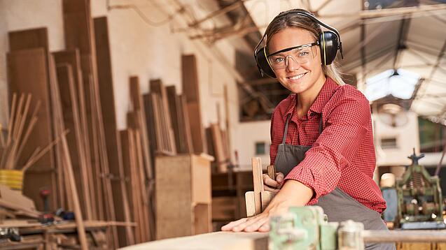 Junge Tischlerin bei der Arbeit an einem Holzstück.