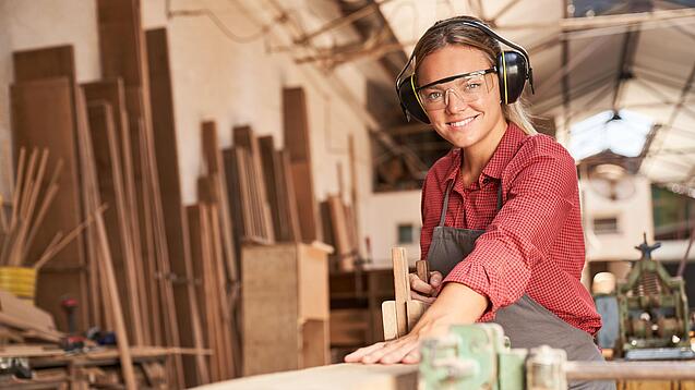 Junge Tischlerin bei der Arbeit an einem Holzstück.