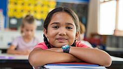 Ein Mädchen lehnt sich mit den Armen auf einen Stapel Schulhefte.