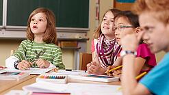 Grundschulkinder sitzen in einem Klassenraum.