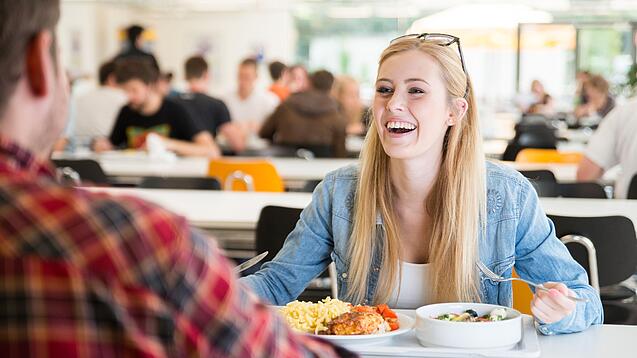 Studierende beim Mittagessen in einer Mensa.