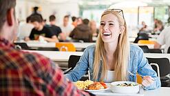 Studierende beim Mittagessen in einer Mensa.