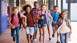 Eine Gruppe Kinder rennt auf dem Pausenhof in Richtung der Kamera.