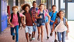 Eine Gruppe Kinder rennt auf dem Pausenhof in Richtung der Kamera.