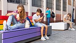 Jugendliche auf einer Bank an einem Handy