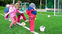Kindergartenkinder spielen Fußball auf einem Fußballfeld.