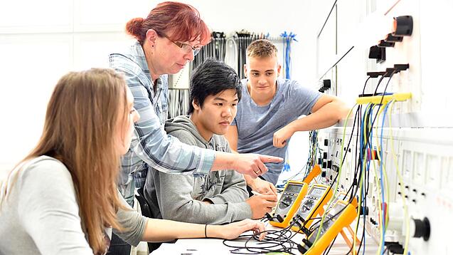 Junge Menschen lernen etwas in einem Elektrofachbetrieb.